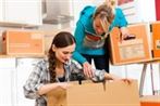 Young women - presumably friends - with moving box in her house moving in or out of a apartment, focus on moving box