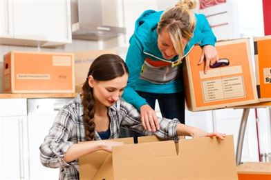 Young women are packing with cardboard boxes